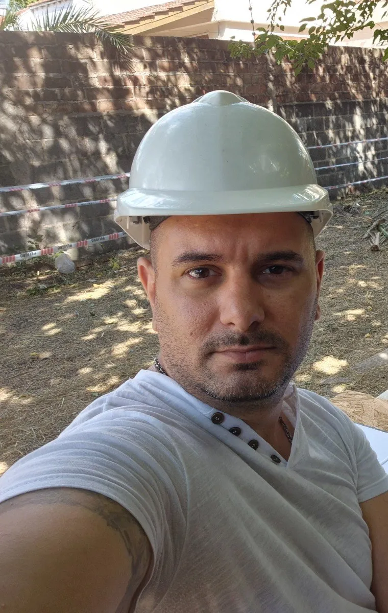 Arq. Damián Bordigoni con casco en una obra, revisando planos