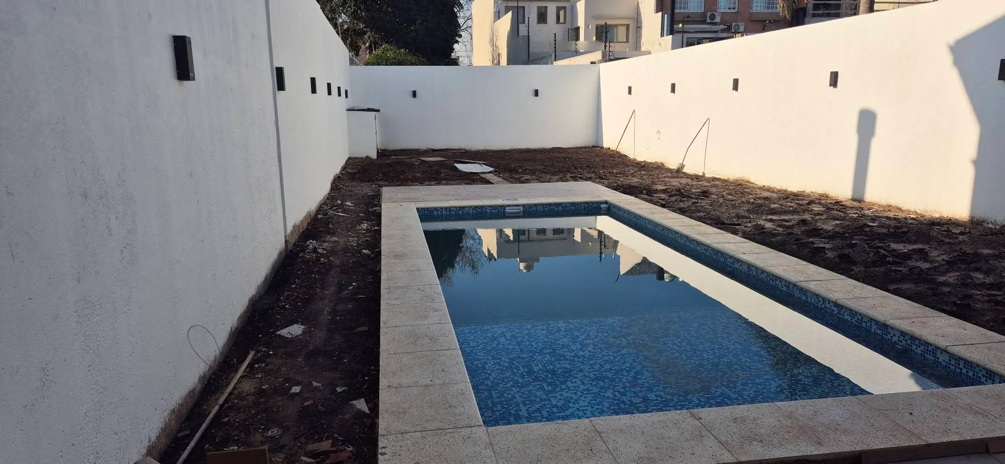 Pileta con venecitas terminada y patio con solado de piedra